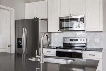 a modern kitchen with stainless steel appliances and white cabinets at Alexandria of Carmel Apartments, Carmel
